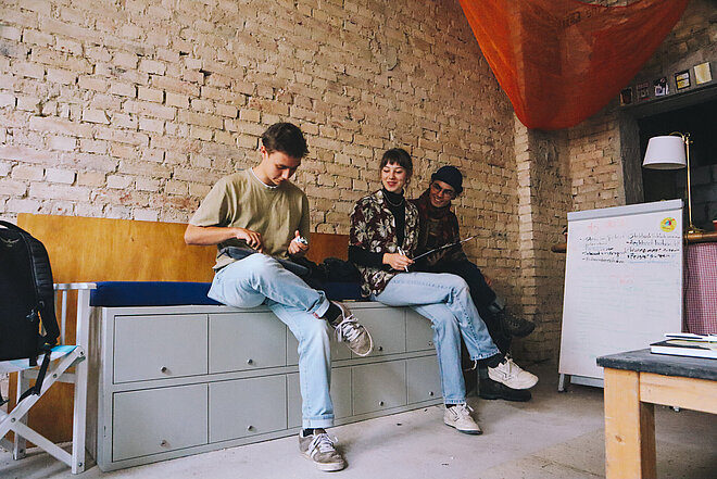 Drei Jugendliche, die auf einer Bank sitzen