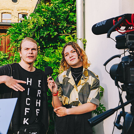 Zwei Jugendliche stehen vor einer Kamera