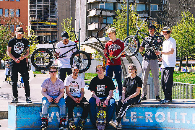 Eine Gruppe Jugendlicher, die mit Fahrrädern auf dem Skateplatz sitzen