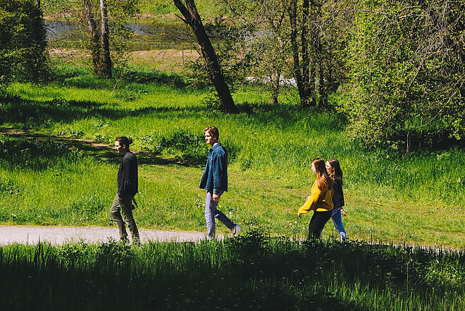 Vier Personen, die durch eine Grünfläche laufen
